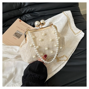 Detailed view of beige straw clutch with pearl embellishments and gold metal frame