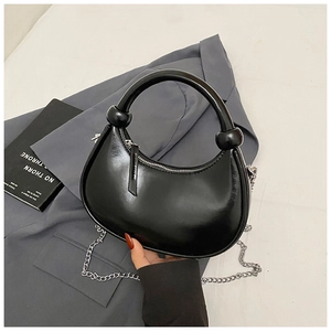 Detail of black leather crescent bag featuring iconic knotted handle and silver chain