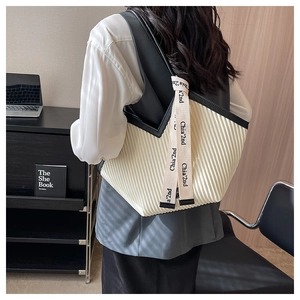 Gros plan détaillé du sac cabas plissé crème avec ruban de marque et bordures noires élégantes