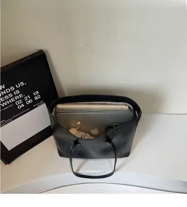 Top view of spacious black tote bag interior showing laptop and daily essentials