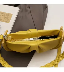 Close-up of yellow lychee pattern PU leather crossbody bag with silver zipper detail