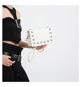 Close-up of white quilted crossbody bag with silver rivet studs and a detachable strap