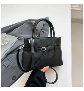 Detail of black pebbled leather tote bag with metal buckle and adjustable strap