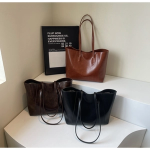 Detailed view of minimalist leather tote bags in black, dark brown, and brown shades