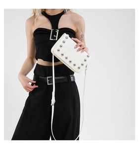 Detail of white leather shoulder bag with silver metallic studs and adjustable strap