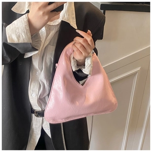 Close-up of pink glossy pleated handbag with triangle silhouette and silver metal chain