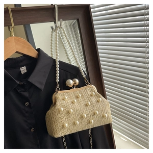 Detailed view of beige straw woven bag with pearl embellishments and vintage clasp