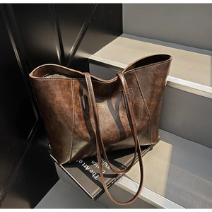 Detail of large brown tote bag with marble texture on dark industrial stairs