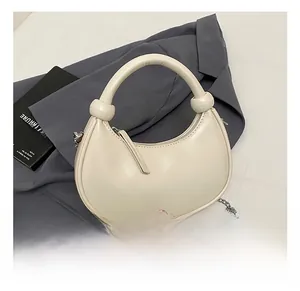 Detail of cream white half-moon bag with knotted handle and silver chain strap