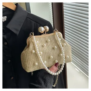 Detail of beige straw clutch with pearl accents, gold frame and dual chain straps
