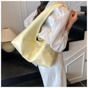 Vue latérale détaillée du grand sac hobo en cuir jaune clair porté à l'épaule du modèle