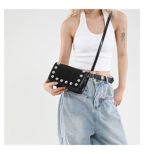 Dettaglio di una borsa a tracolla punk con borchie argentate su materiale nero lucido