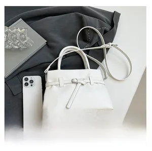 Litchi pattern white crossbody bag with buckle detail shown in lifestyle setting