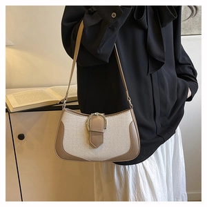 Detail of minimalist beige canvas and brown leather underarm bag with metal buckle