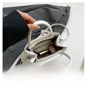 Interior view of small white leather tote showing phone and makeup items inside