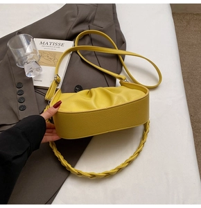 Detailed close-up of yellow pleated leather bag with twisted handle and litchi texture