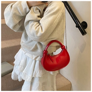 Bright red crescent bag with a decorative knot handle and elegant metal chain strap