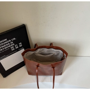 Interior view of large brown tote bag showing gray lining and zippered pocket
