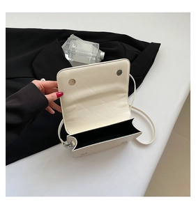 Detail view of the magnetic closure and black interior lining of the white PU leather bag