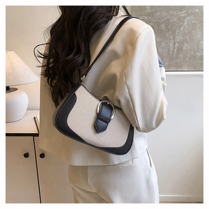 Detail of minimalist canvas and black leather shoulder bag with silver horseshoe buckle