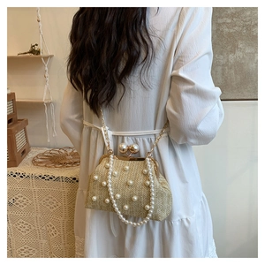 Detail view of woven straw crossbody bag with pearl accents worn on a summer outfit