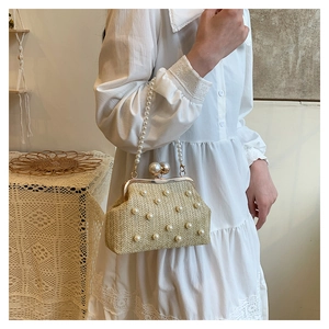Detailed view of straw handbag with pearl embellishments and gold metal frame clasp