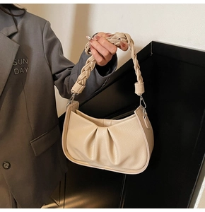 Detail of off-white lychee texture leather bag with woven handle and pleated cloud design