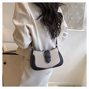 Detailed side view of a large two-tone contrast shoulder bag on a female model