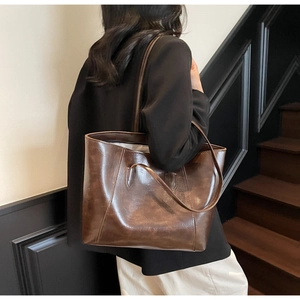 Detail of a large brown oil-wax leather tote bag showing vintage texture and slouchy drape