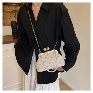 Close-up of straw woven evening bag featuring pearl accents and gold metal ball clasp