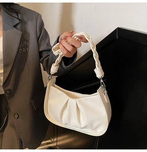 Close-up of cream underarm bag showing gathered pleats and woven handle detail