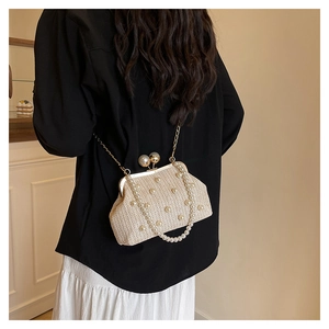 Detail of beige woven straw bag with pearl embellishments and golden metal clasp