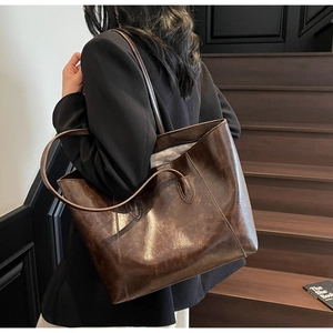 Detail of dark brown faux leather tote bag with vintage wax texture and reinforced straps