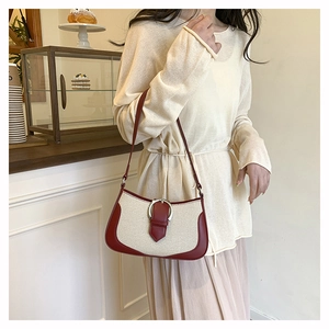 Detail of minimalist canvas and burgundy leather underarm bag with silver round buckle