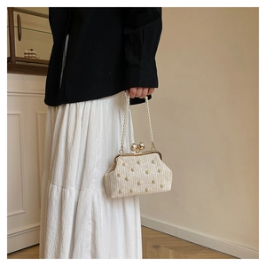Detailed shot of cream straw bag with pearl embellishments and elegant pearl handle