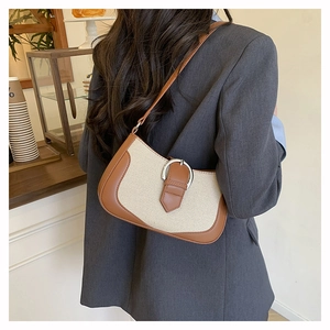 Detail of canvas shoulder bag with brown leather trim and silver horseshoe buckle