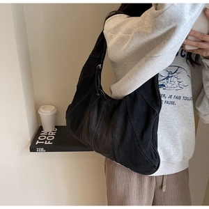 Fashionable black patchwork denim hobo bag worn by model in a stylish indoor setting