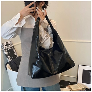 Selfie miroir montrant un cabas noir en cuir verni brillant avec une large bandoulière
