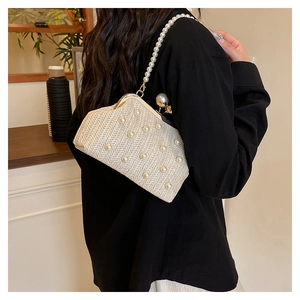 Detail of straw woven clutch bag with pearl handle and vintage gold metal clasp closure