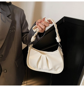 Close-up of cream pleated hobo bag with stylish woven handle and silver metal hardware