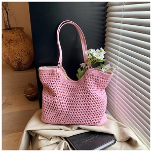 Chic pink woven tote bag with leather handles and interior daisy decor for beach vacation