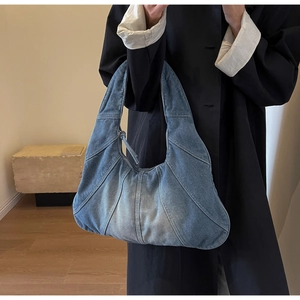 Detail view of retro blue patchwork denim tote bag worn with a long black coat