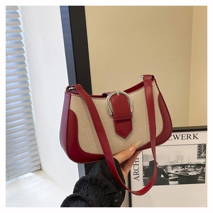 Detail of red leather and beige woven fabric underarm bag with silver horseshoe buckle