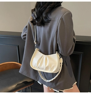 Detail of white pleated dumpling bag with textured lychee leather and woven handle