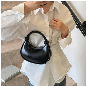 Black glossy semi-round handbag with silver chain and metal ring handle shown on a model