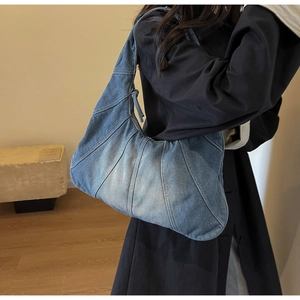 Detail of vintage patchwork denim hobo bag featuring contrast stitching and washed finish
