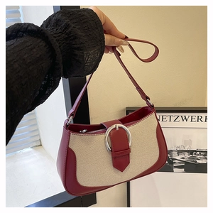 Detail of burgundy leather and canvas patchwork bag with a large silver ring buckle