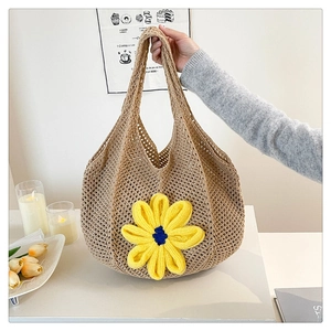 Close-up of khaki hand-woven straw tote bag featuring a bright yellow sunflower detail