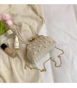 Detail of cream woven evening bag with pearl embellishments and vintage gold metal clasp