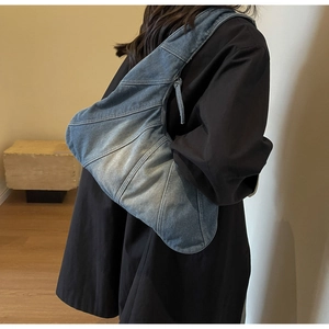 Detailed view of the washed denim fabric texture and stitching on the crescent shoulder bag